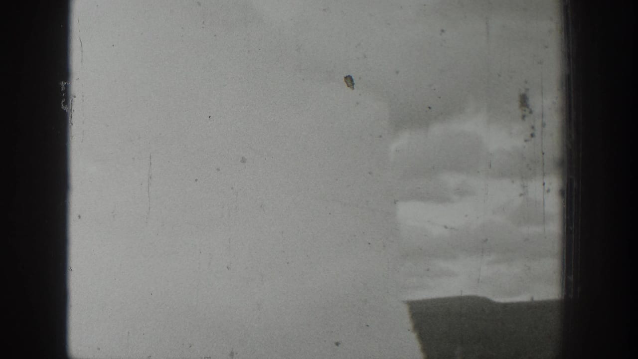 1939 Wyoming 8mm frame showing a distant water or steam eruption partly obscured by dark vertical window-like bars.