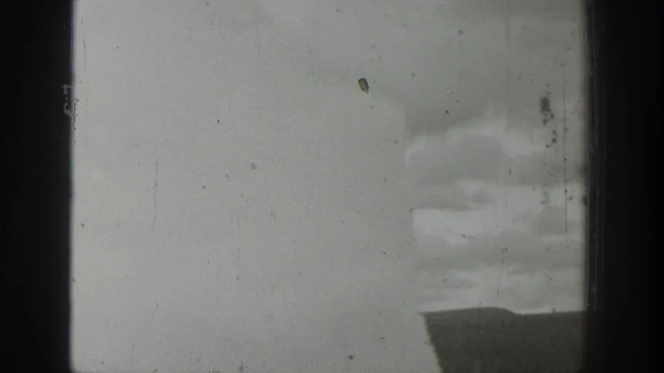 1939 Wyoming 8mm frame showing a distant water or steam eruption partly obscured by dark vertical window-like bars.