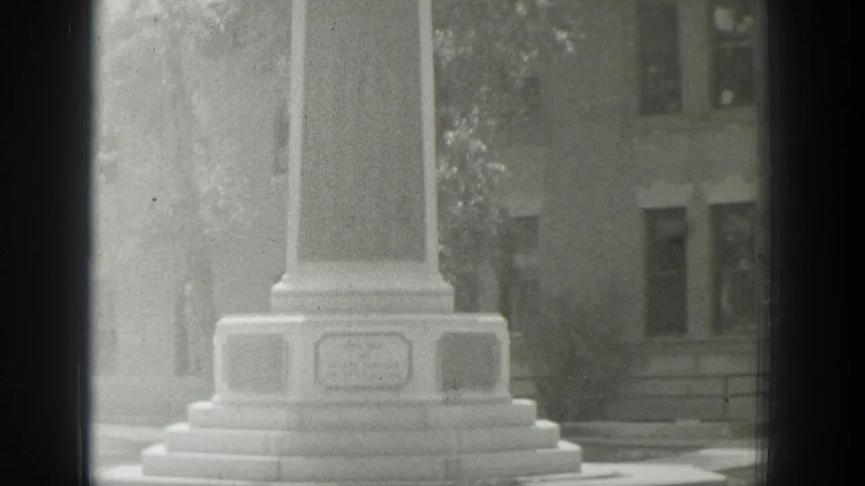Black-and-white 1939 Wyoming home-movie frame showing the stepped base of a memorial with engraved plaques.