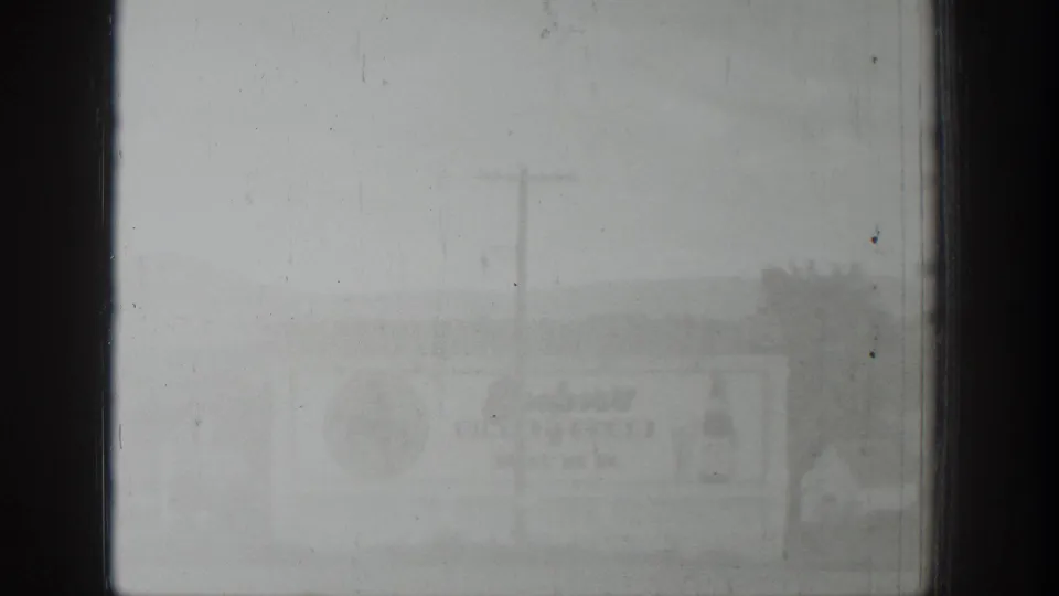 Soft black-and-white 1939 Wyoming frame showing a distant weathered billboard with indistinct text and a foreground utility pole.