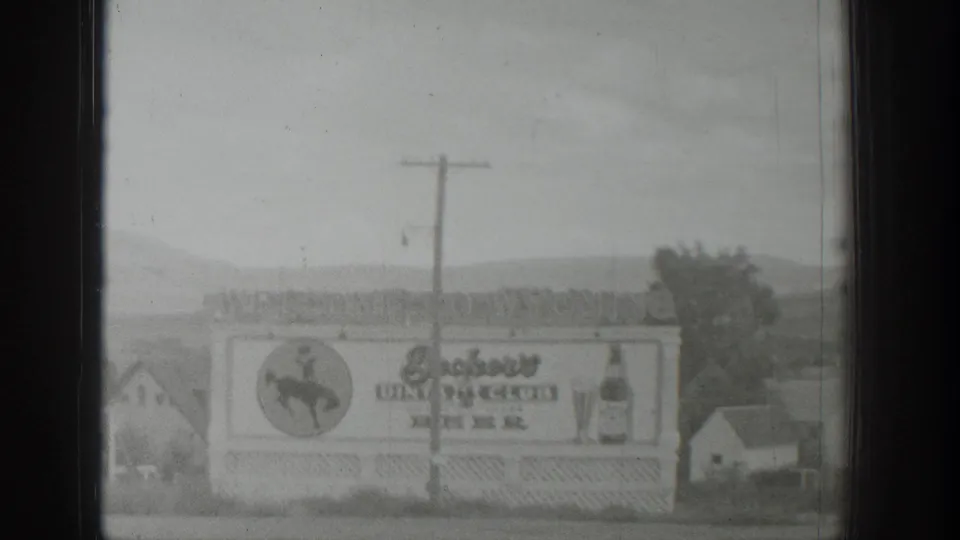 1939 Wyoming roadside view of the dining club and beer billboard, partly crossed by a utility pole, with low hills in the background.