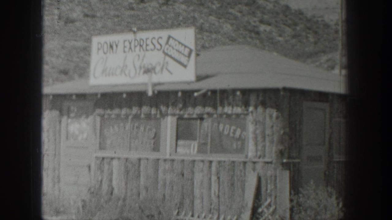 Similar view of the roadside food stand with sign, awning roof, and rough wood siding.