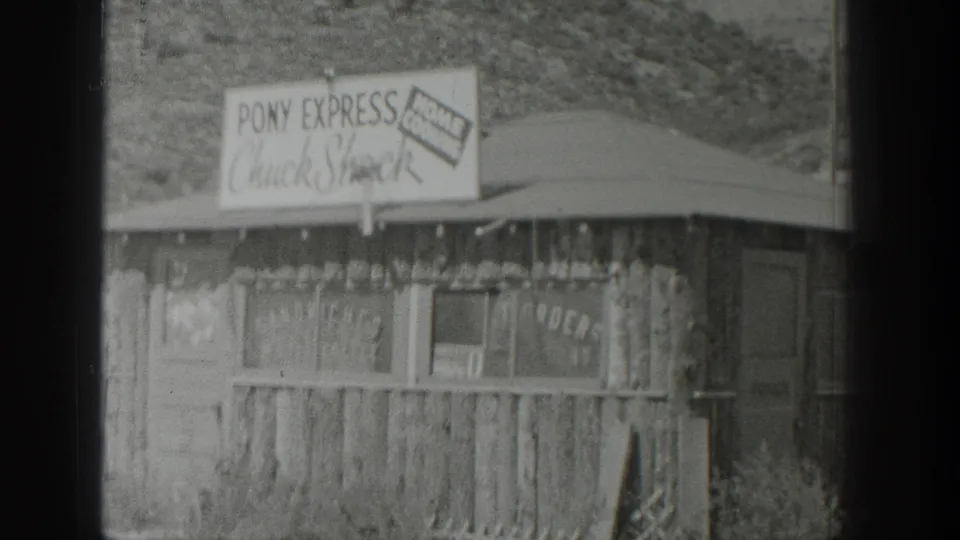 1939 Wyoming home-movie frame of the Pony Express Chuck Shack, with signage, rough timber siding, and open hillside setting.