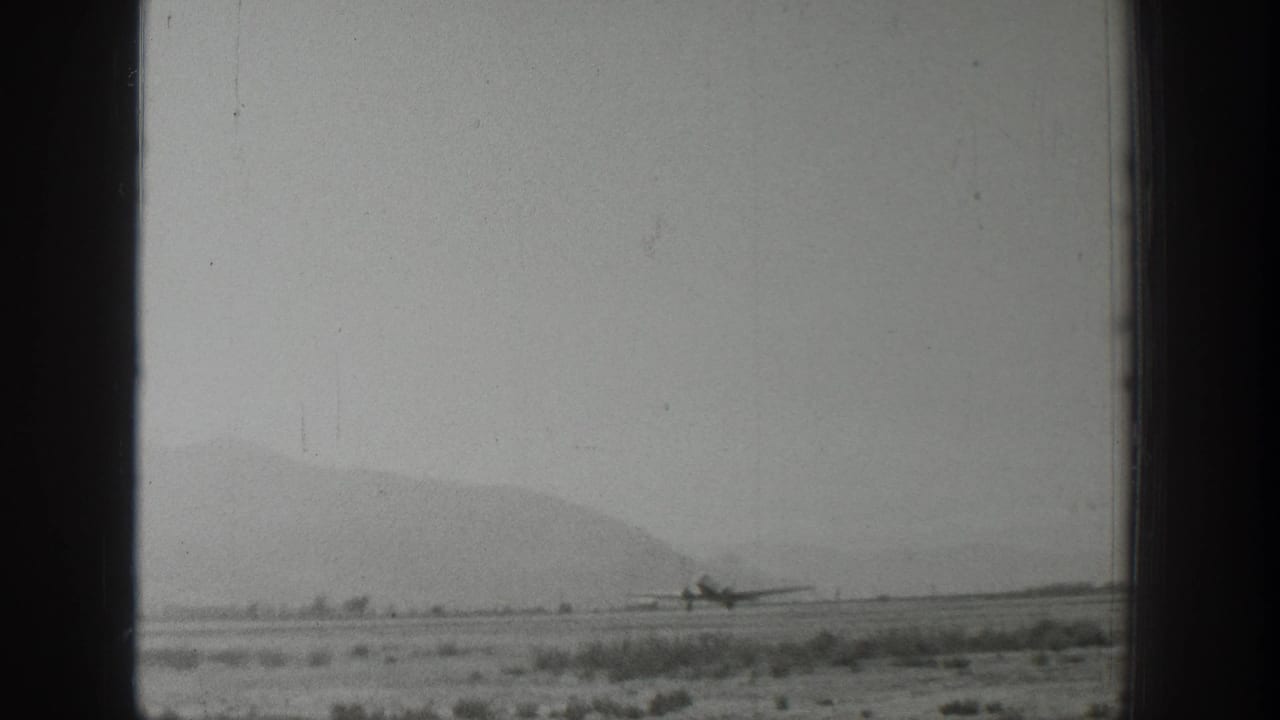 Propeller airplane moving along the runway near a distant mountain ridge.