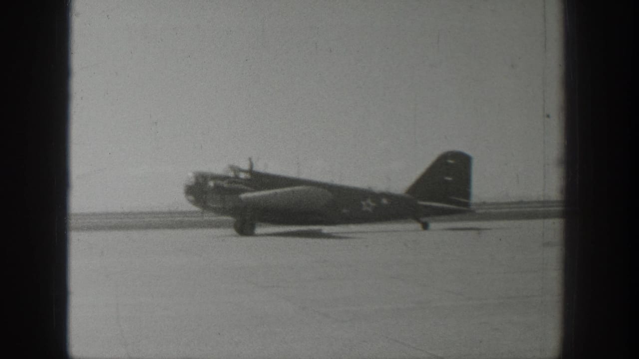 Propeller aircraft with U.S. star insignia positioned on an open runway.