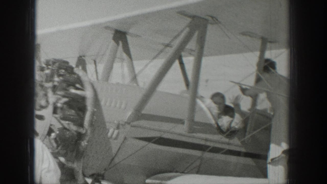 1939 Wyoming frame with a pilot in an open cockpit and onlookers gathered near the biplane wing and fuselage.