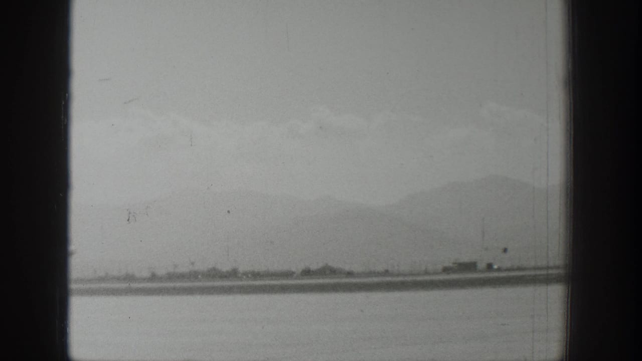 Wyoming 1939 airstrip view with no aircraft centered, showing a low runway line, faint structures, mountains, and foreground framing.