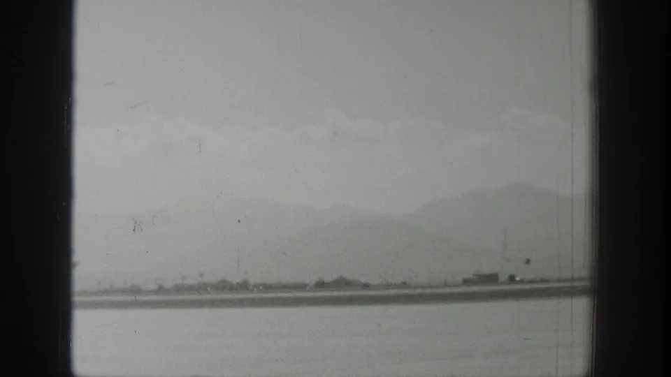 Wyoming 1939 airstrip view with no aircraft centered, showing a low runway line, faint structures, mountains, and foreground framing.