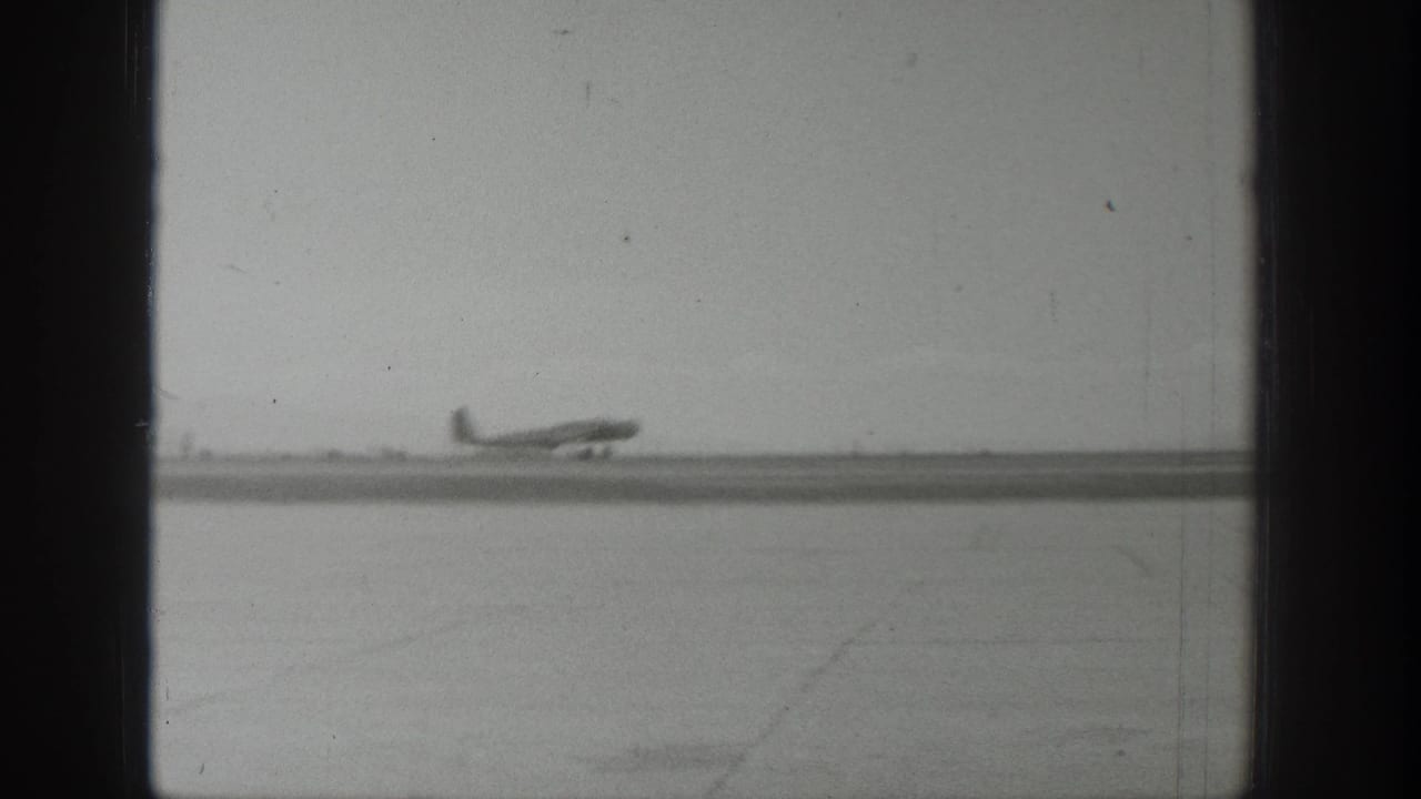 Propeller airplane moving along a runway beside a wide open airfield.