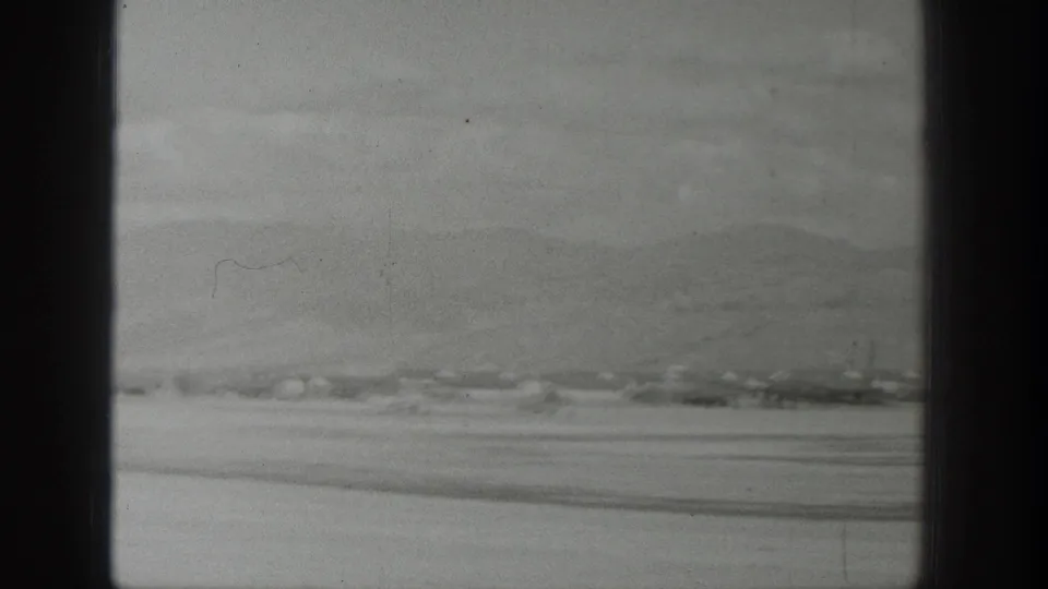 Soft 8mm aerial frame from Wyoming showing a pale water or river surface, shoreline bands, and dark aircraft-window edges.
