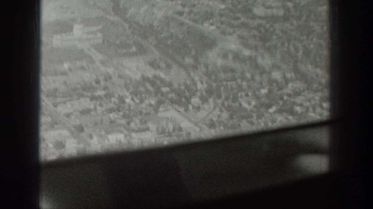 Black-and-white 1939 Wyoming home-movie frame looking down through an airplane window at roads, buildings, and open ground.