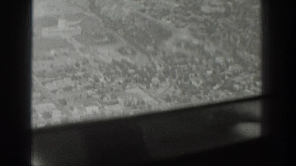 Black-and-white 1939 Wyoming home-movie frame looking down through an airplane window at roads, buildings, and open ground.