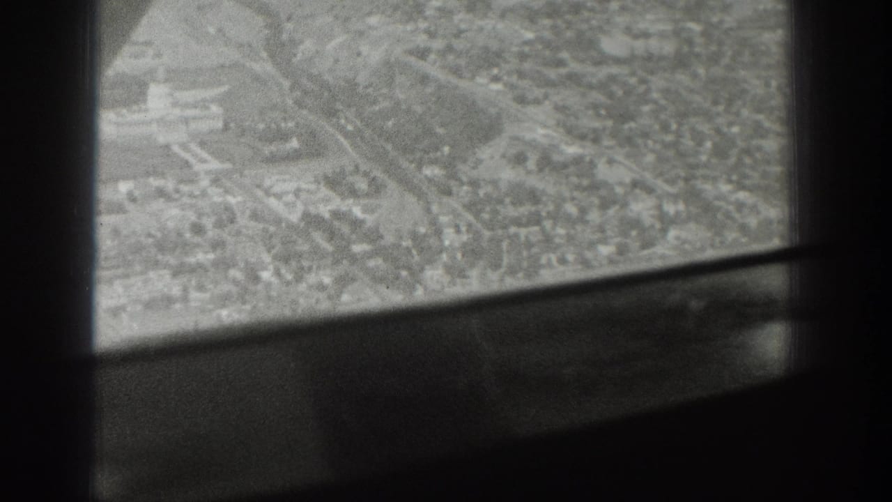 High aerial view of a town partially blocked by plane window bars.