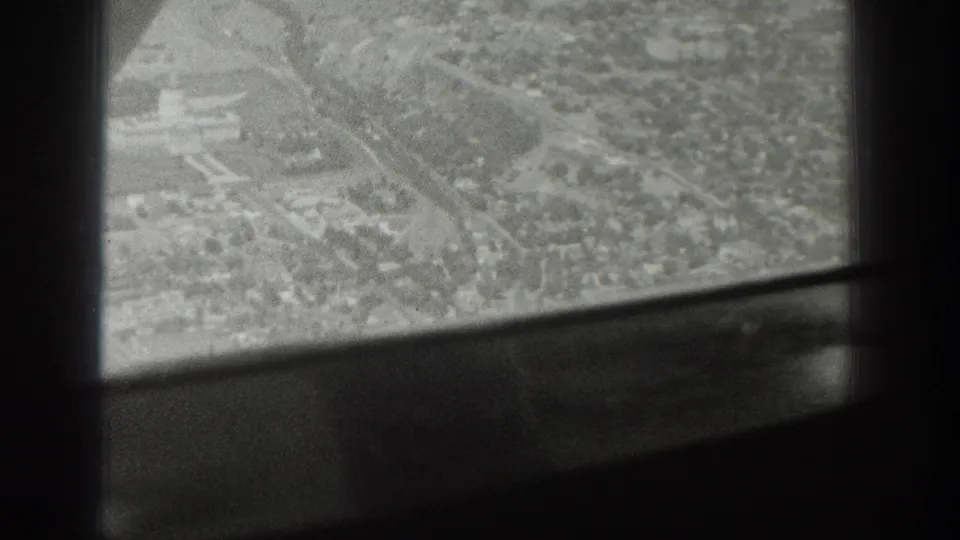 Black-and-white aerial frame over a Wyoming town, with dark aircraft window structure crossing the view.