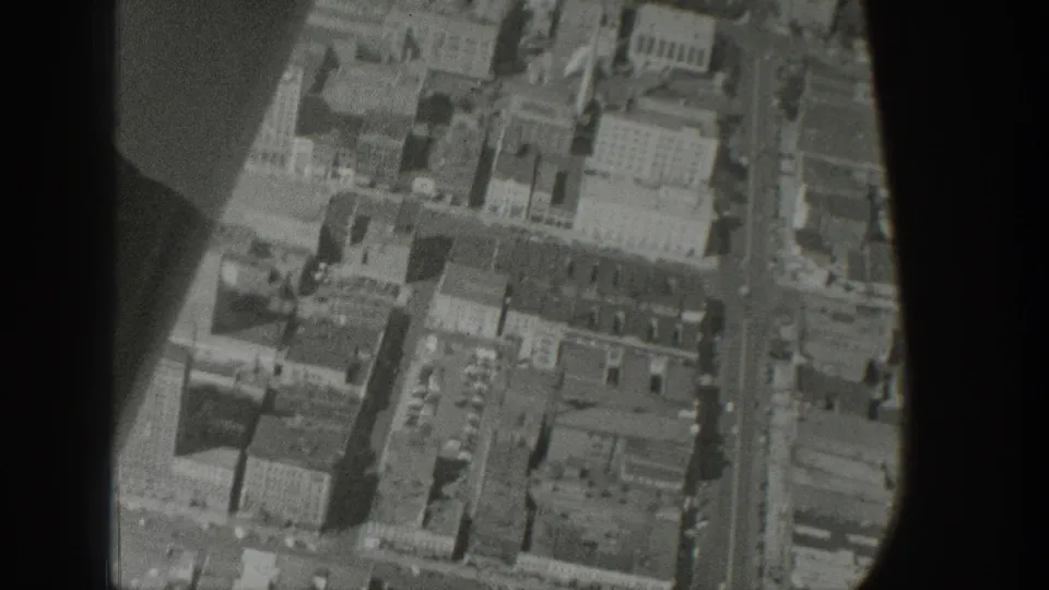Black-and-white Wyoming aerial frame showing a dense block of buildings and streets from a plane-window perspective.