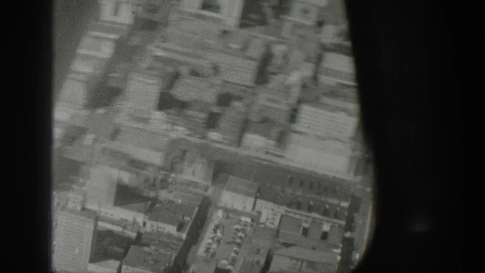 1939 Wyoming home-movie frame showing a soft aerial view of dense city blocks and streets through dark aircraft framing.