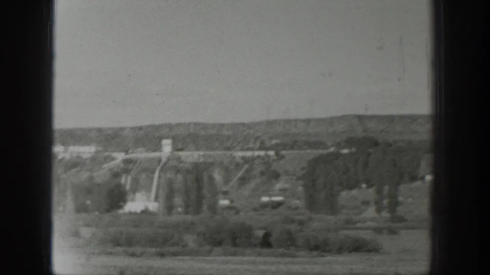 1939 Wyoming aerial home-movie frame showing open countryside, trees, and distant low hills beyond the window framing.