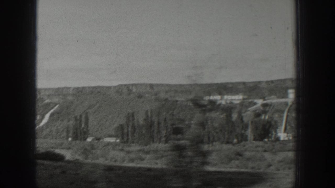 Rolling hillside with distant buildings and dark window bars in the foreground.