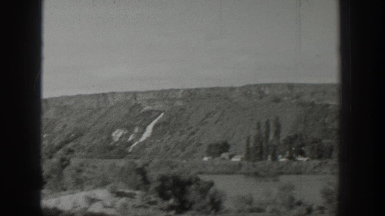 1939 Wyoming 8mm frame with a broad hillside, scattered trees, open fields, and pale hillside markings in soft focus.