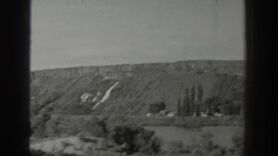 1939 Wyoming 8mm frame with a broad hillside, scattered trees, open fields, and pale hillside markings in soft focus.