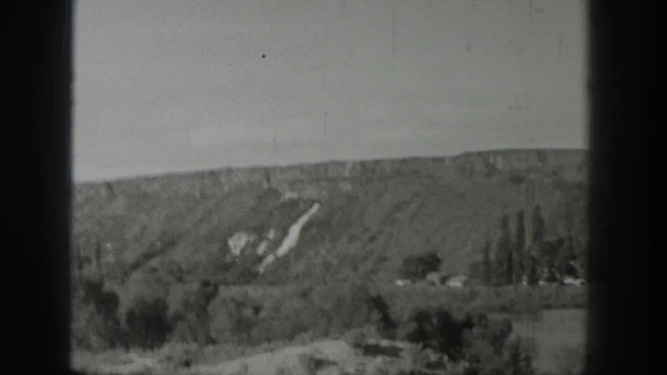 1939 Wyoming landscape frame showing a soft hillside view, tree clusters, field areas, and dark vertical film borders.
