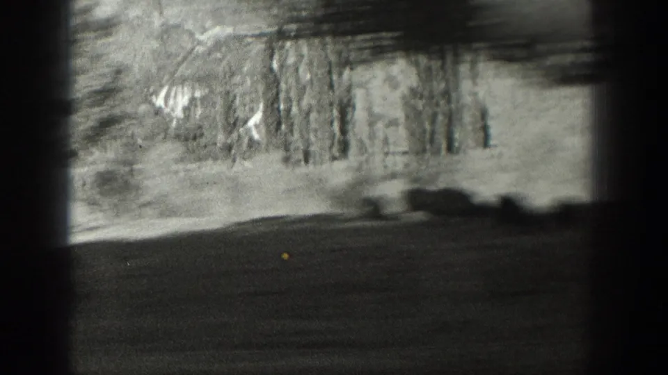 1939 Wyoming home-movie frame with blurred roadside trees, dark foreground, and strong film-frame borders suggesting motion.