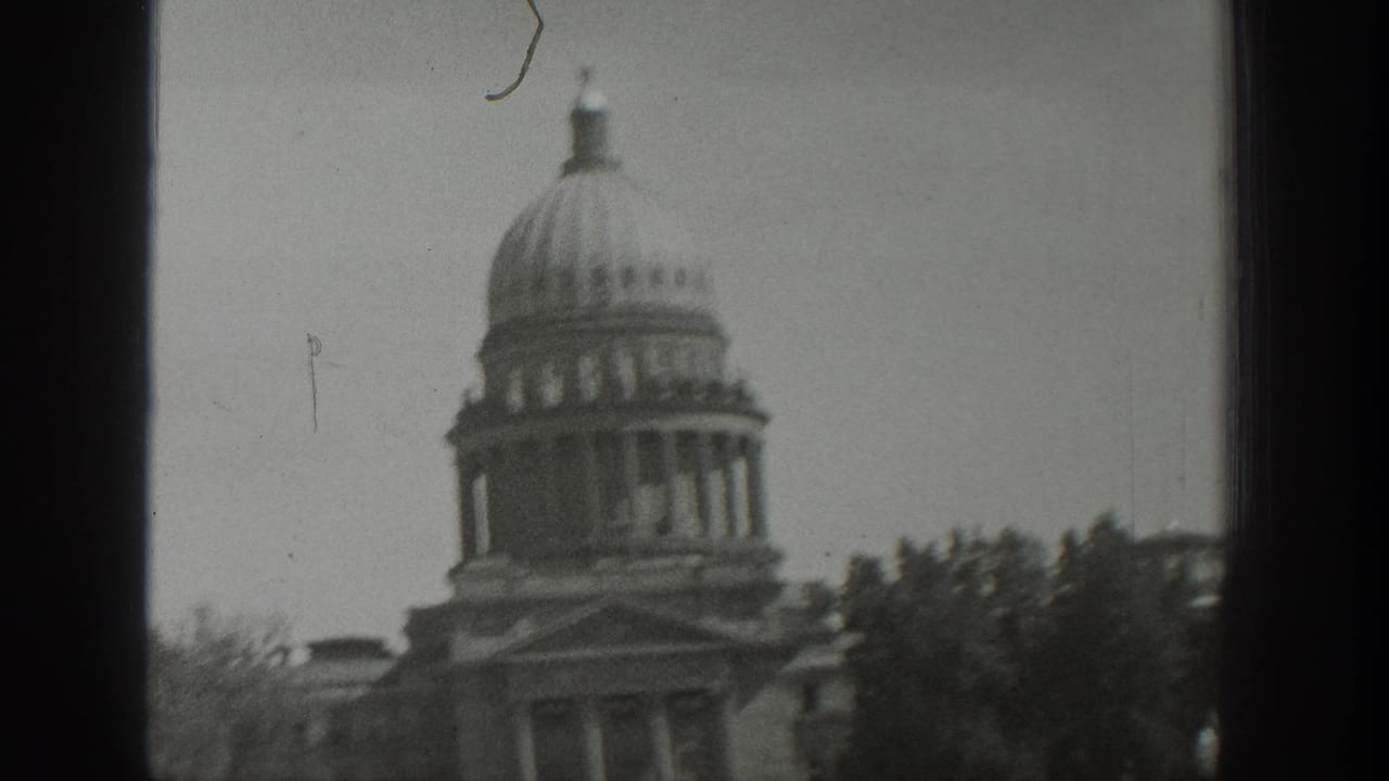 1939 Wyoming home-movie view of a domed government-style building partially obscured by window framing and trees.