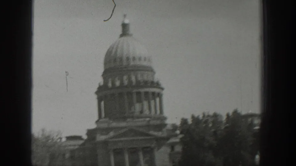 1939 Wyoming home-movie view of a domed government-style building partially obscured by window framing and trees.