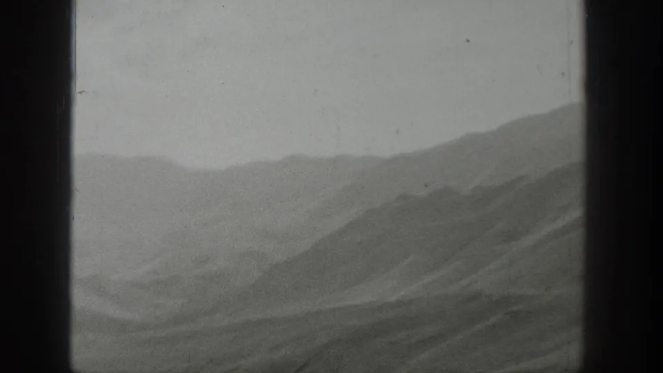 1939 Wyoming 8mm frame showing layered mountain ridges through a window, with soft haze and visible film grain.