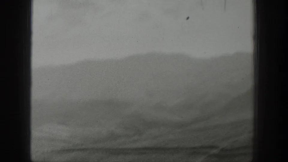 A hazy Wyoming mountain landscape fills the frame, divided by dark window edges in 1939 8mm footage.