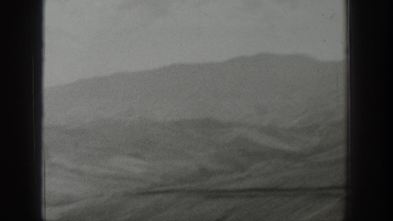 1939 Wyoming home-movie view of hazy mountain ridges seen through a dark window frame from a moving vehicle.