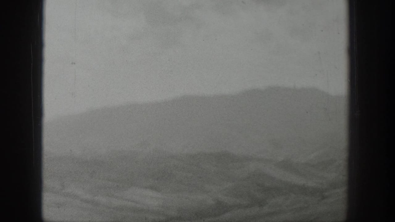 Soft mountain range and foothills divided by a vertical window bar.