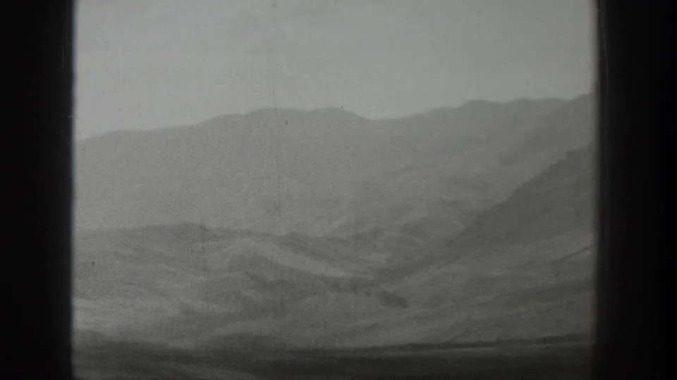 Hazy Wyoming ridges are visible through the train window, with a dark center divider and muted black-and-white 8mm texture.