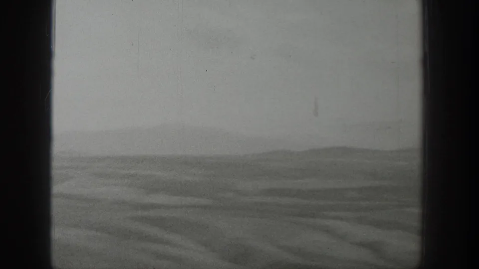 The final frame shows a broad Wyoming plain and distant ridge line through the dark train-window edge, softened by haze and film grain.