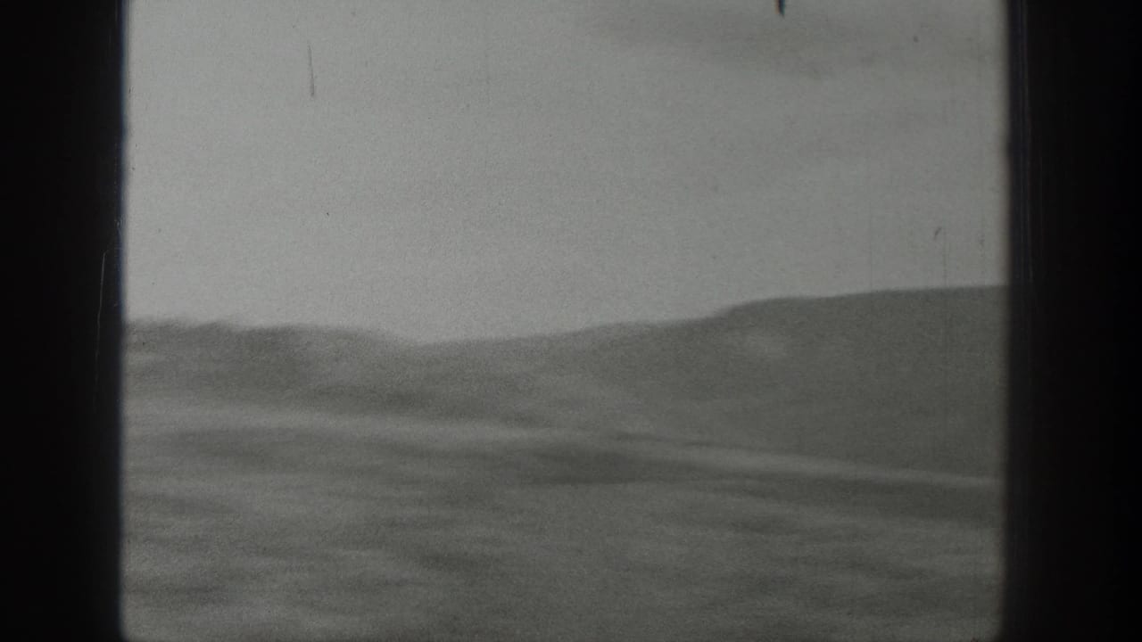 Soft black-and-white view of low desert hills and a pale sky within 8mm borders.