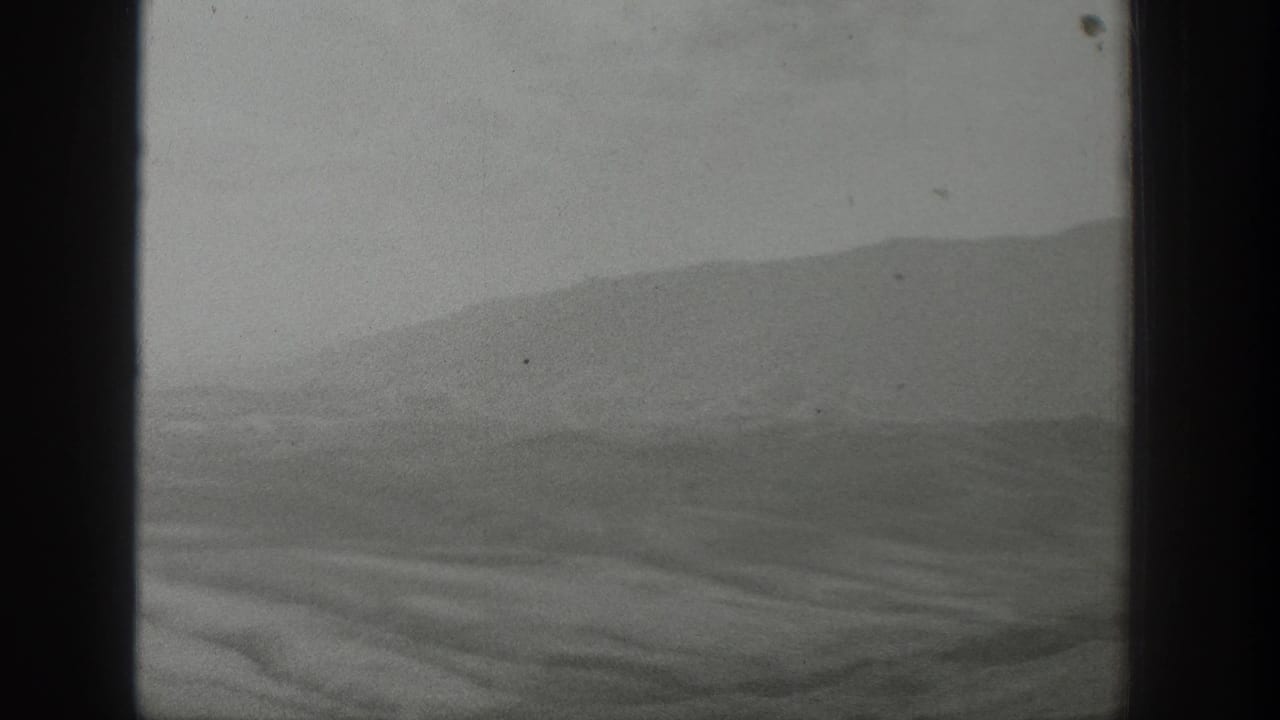1939 Wyoming landscape viewed through a vehicle window, with soft hills and valley forms in black-and-white 8mm footage.