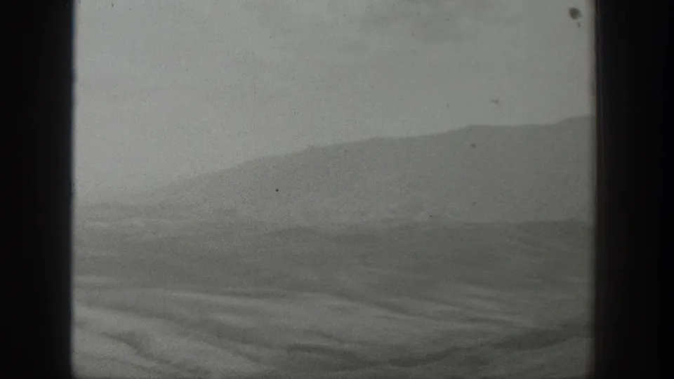 1939 Wyoming landscape viewed through a vehicle window, with soft hills and valley forms in black-and-white 8mm footage.