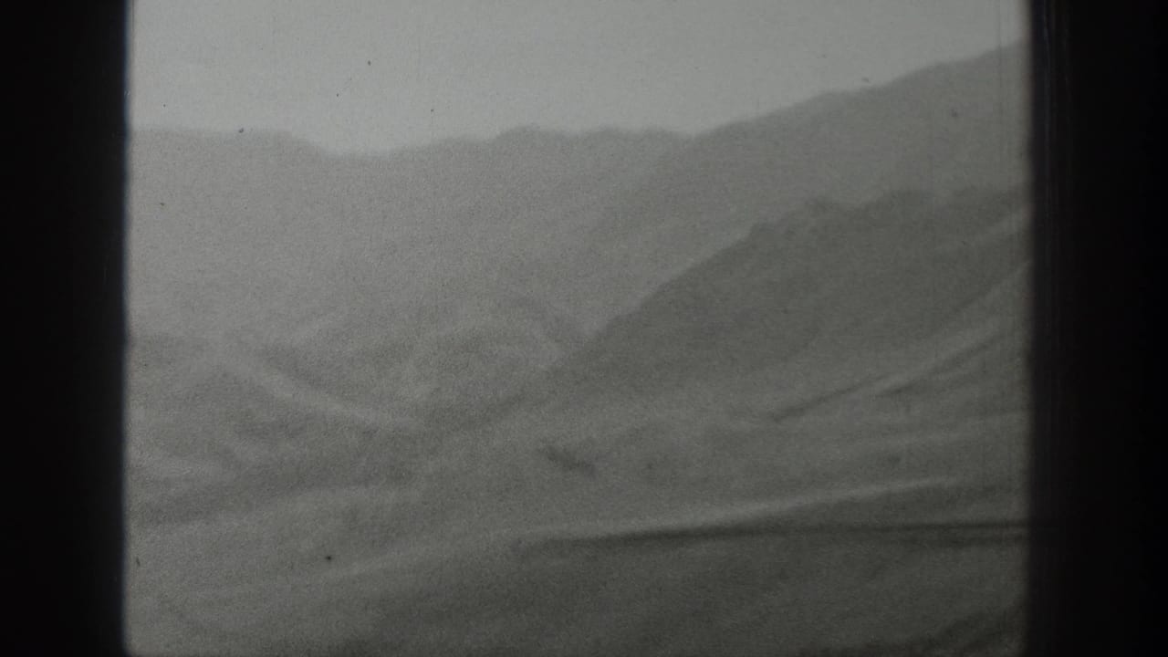 Rolling Wyoming hills and ridges pass behind a central window frame in grainy 1939 home-movie footage.