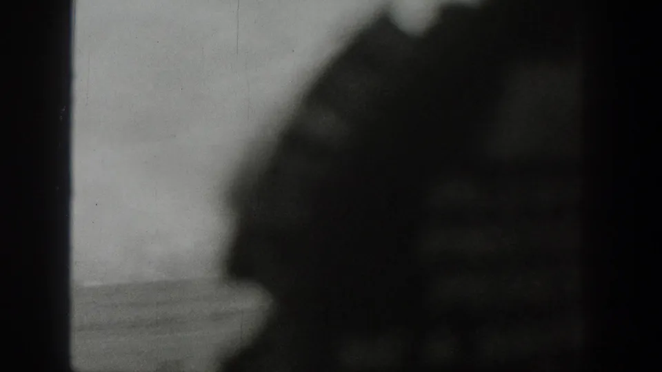 A blurred foreground shape crosses a window-framed 1939 Wyoming landscape, with pale hills still visible beyond.