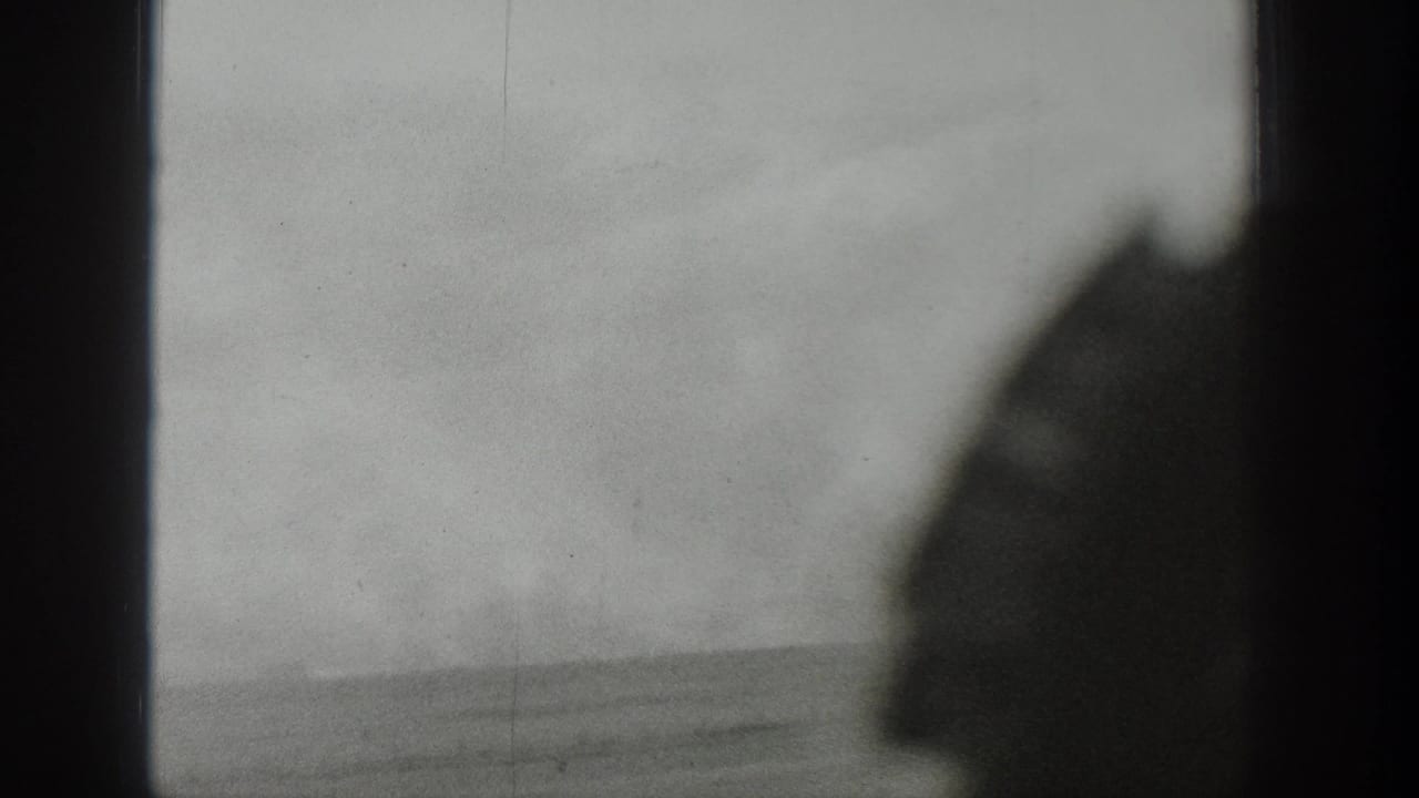 1939 Wyoming 8mm frame looking through a window toward an open, hazy rural landscape under severe wind.