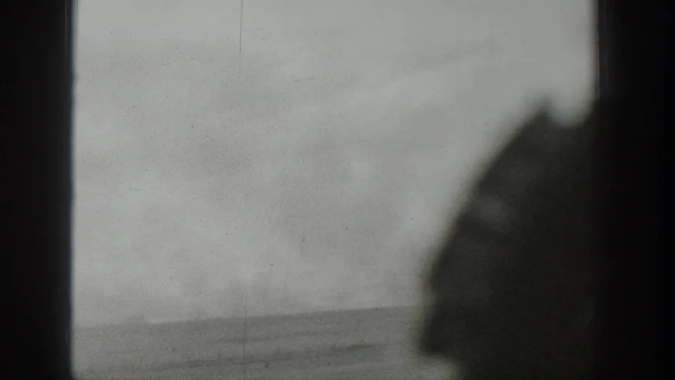 1939 Wyoming 8mm frame looking through a window toward an open, hazy rural landscape under severe wind.