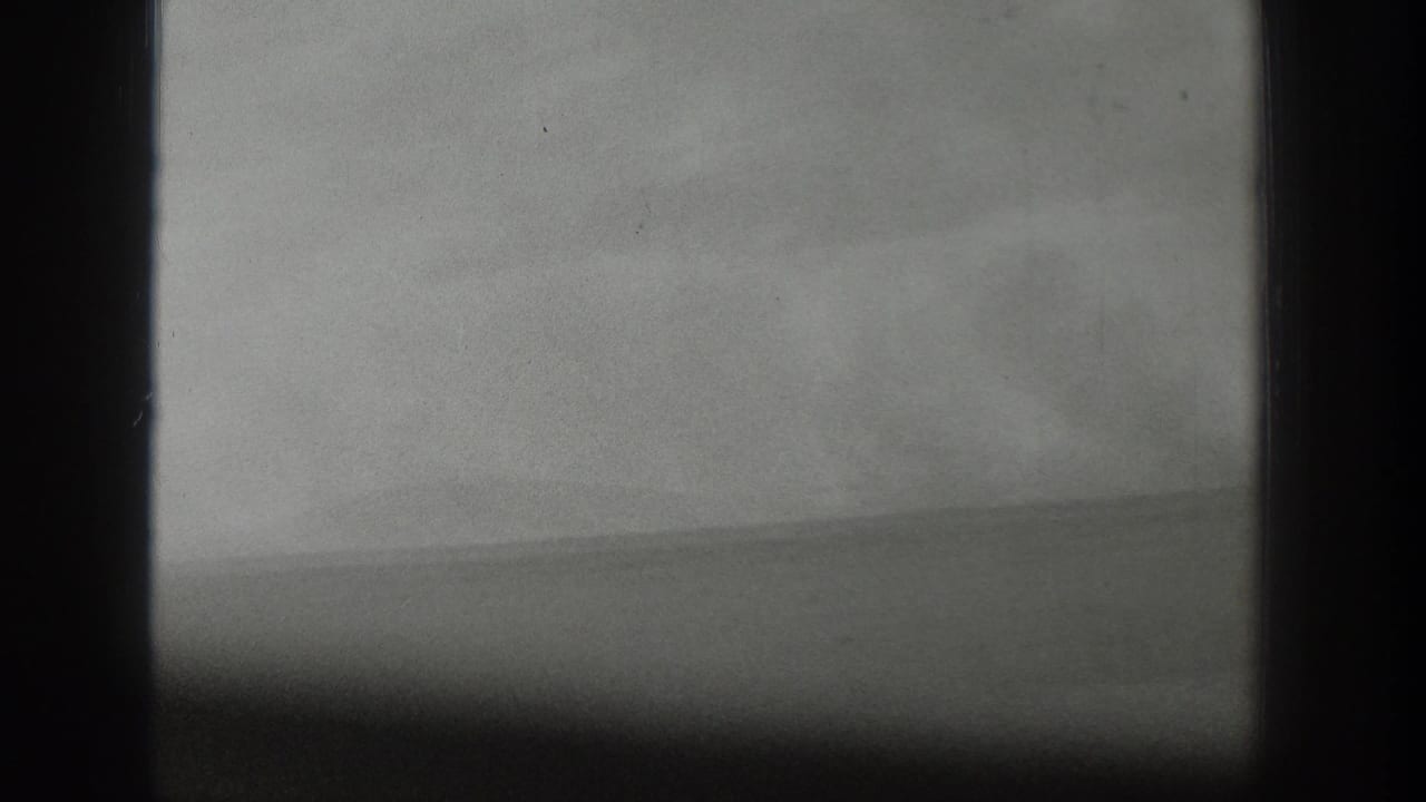 Black-and-white 1939 home-movie frame from Wyoming showing a hazy water horizon seen through dark window bars.
