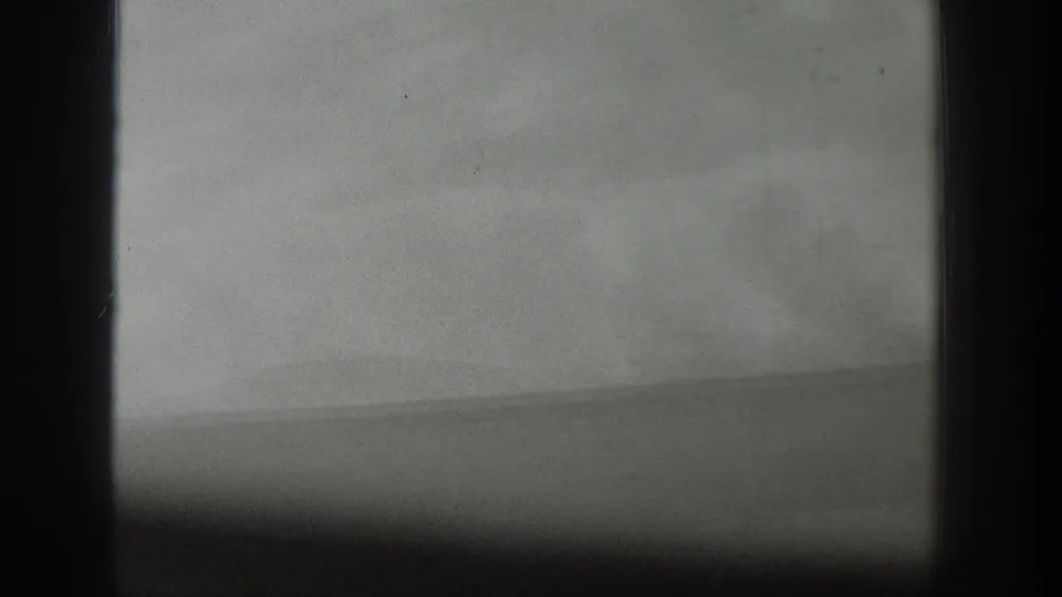 Black-and-white 1939 home-movie frame from Wyoming showing a hazy water horizon seen through dark window bars.