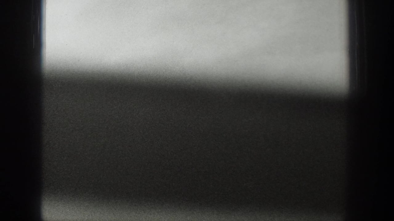 Blurred water and sky partly obscured by a dark window structure.