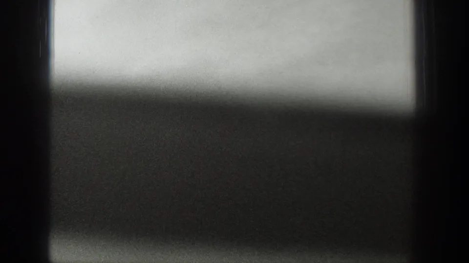 Soft black-and-white view of water and sky, partly blocked by a dark window frame in the 1939 Wyoming footage.
