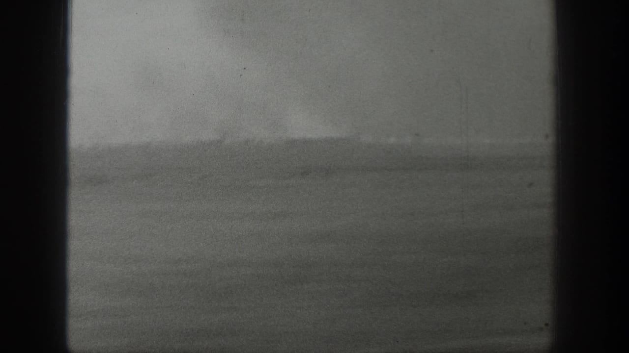 1939 Wyoming 8mm frame showing a low horizon, flat terrain, and a faint pale plume rising in the distance.