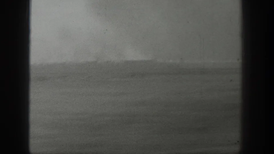 1939 Wyoming 8mm frame showing a low horizon, flat terrain, and a faint pale plume rising in the distance.