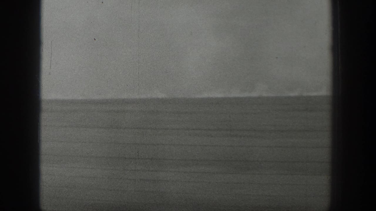 Open grassland horizon with faint smoke and strong vertical dark film borders.