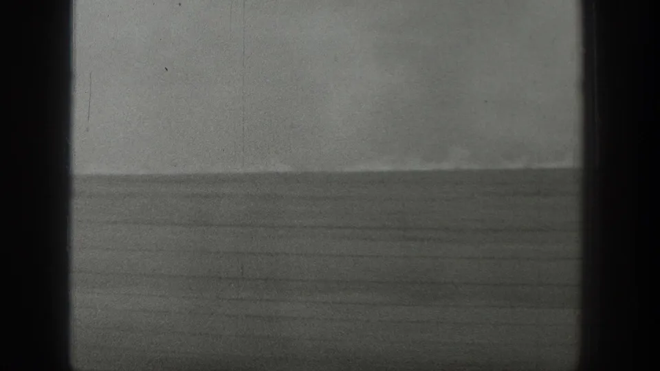 1939 Wyoming 8mm frame with a wide open grassland horizon, faint smoke, and prominent vertical gate borders.
