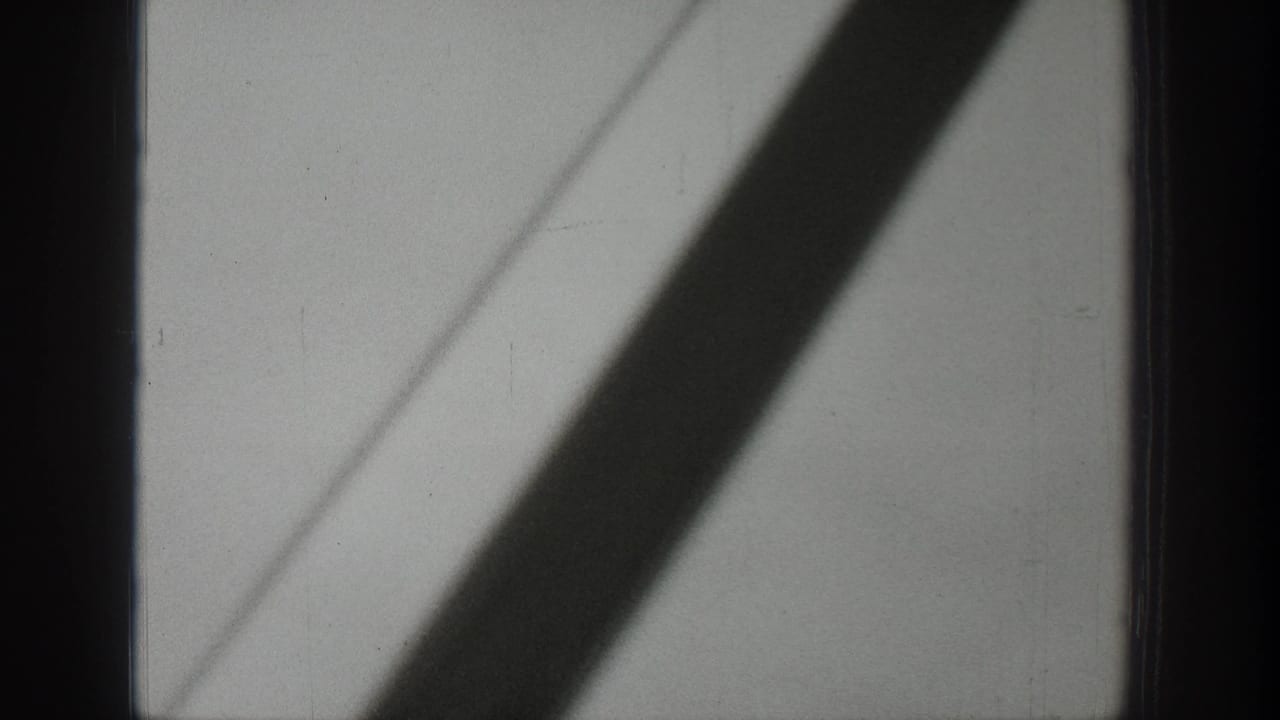 1939 Wyoming 8mm frame showing a pale window or interior panel crossed by a dark diagonal shadow from inside a moving bus.